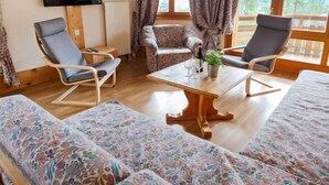 A cozy room with a TV, two chairs, a sofa, and a table with a plant. - Le Bristol A20 by Interhome (Villars)