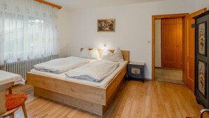 A bedroom with a wooden bed, a nightstand, a radiator, a chair, and a door.