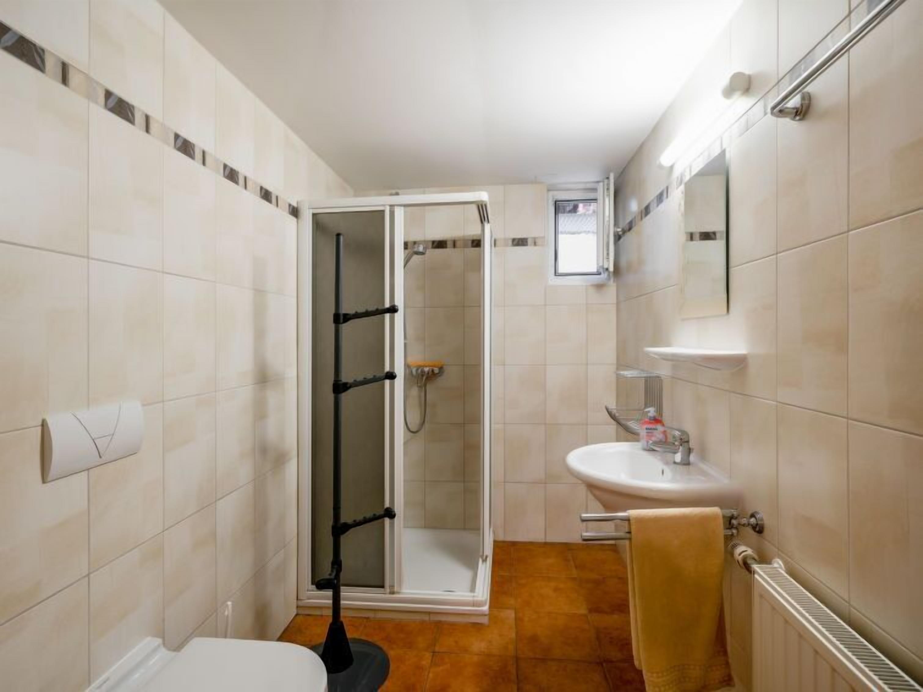 A bathroom with a shower, toilet, sink, and towel rack.