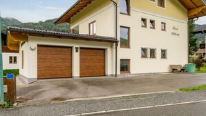 A two-story house with a garage, wooden beams, and a mountain backdrop.