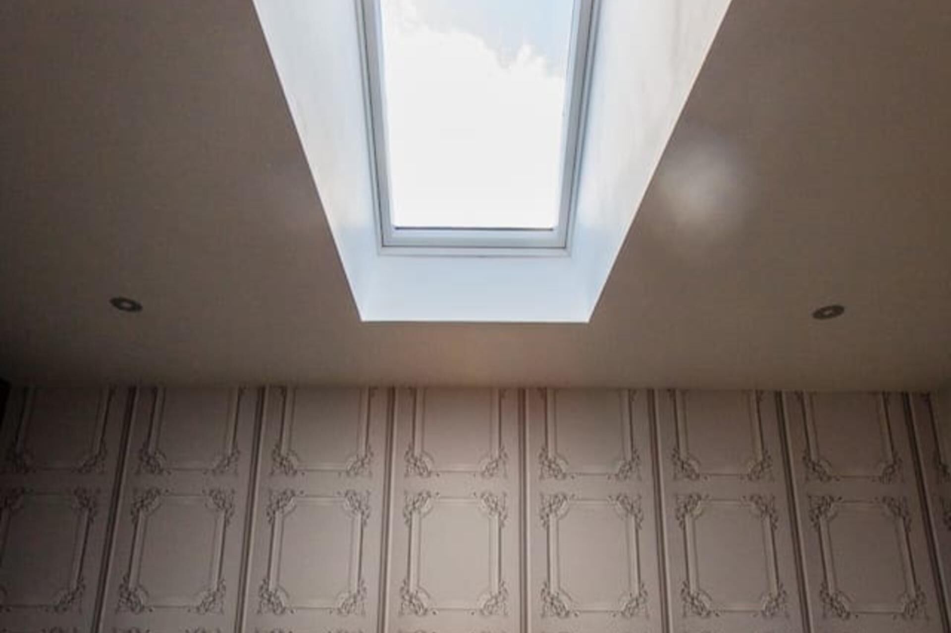 A skylight in a room with patterned walls.