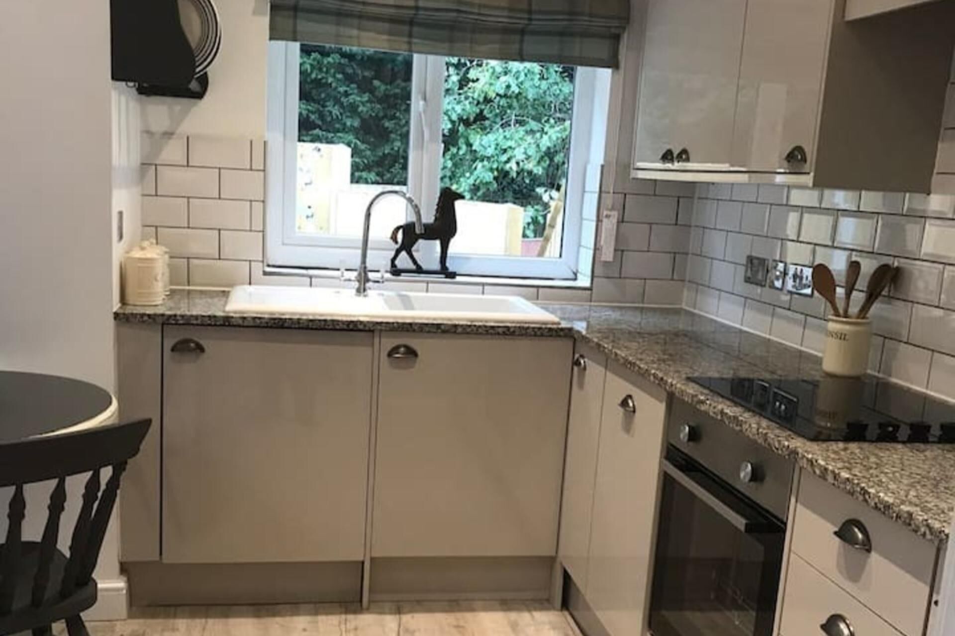 Una cucina con finestra, lavello, pensili e piano cottura.