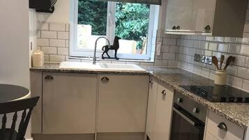 Una cucina con finestra, lavello, pensili e piano cottura.