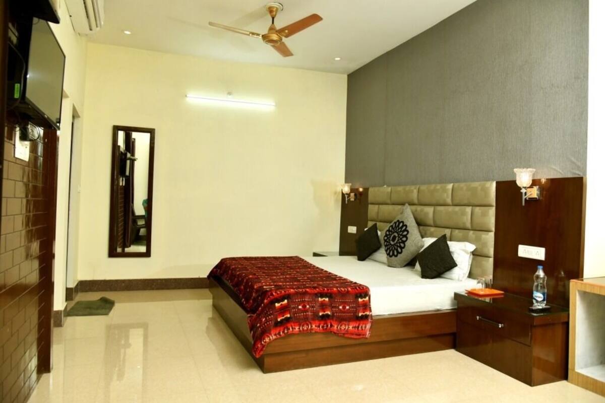 A bedroom with a bed, a nightstand, a bedside table, a mirror, and a ceiling fan.