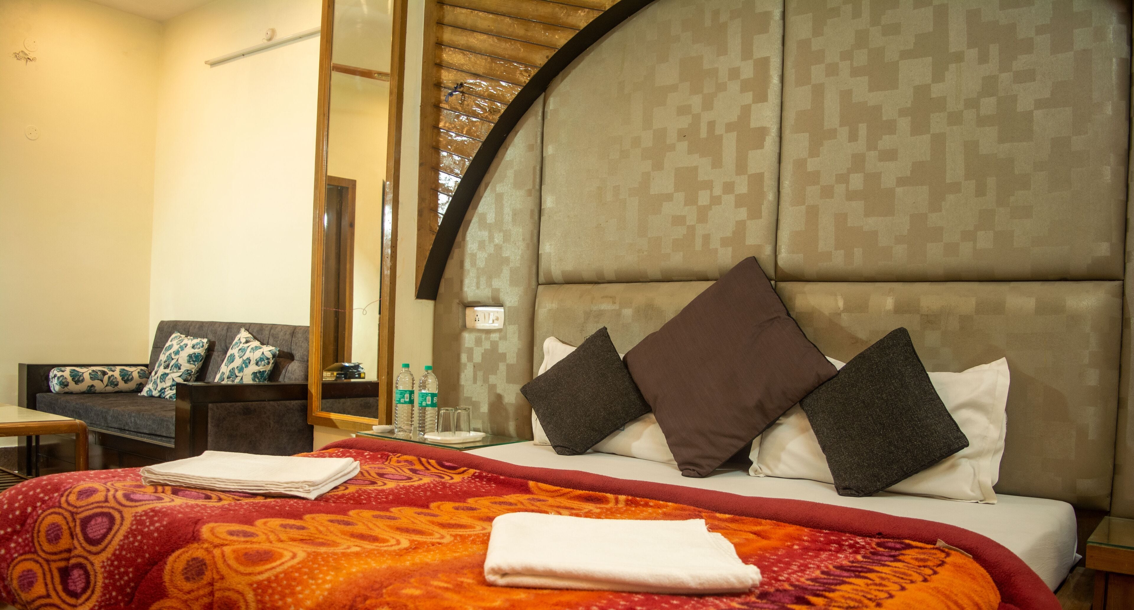 A hotel room with a large bed, a sofa, and a small table.