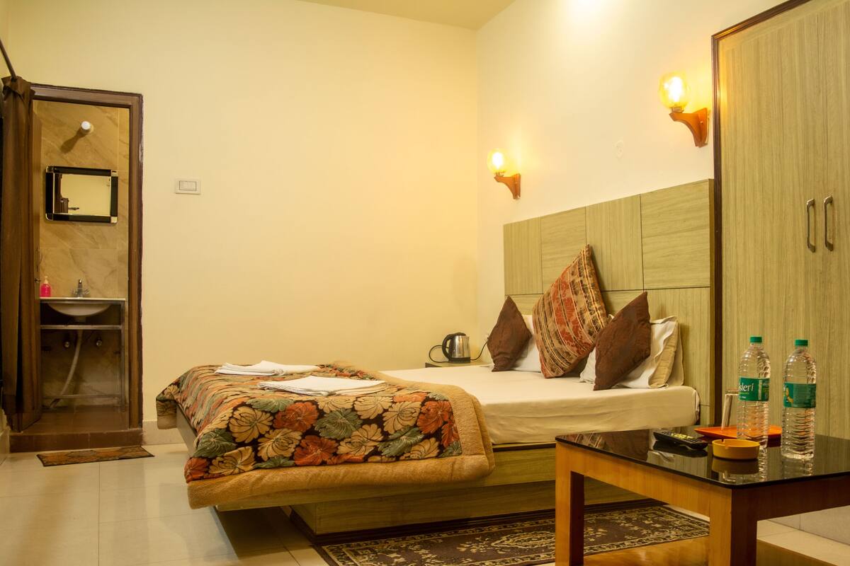 A hotel room with a bed, bedside table, and a wardrobe.