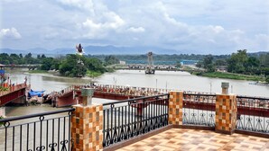 Un río con un puente, una estatua y una estructura roja con gente.