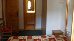 Una habitació amb una porta de fusta, un mirall, una taula petita i un edredó acolxat.