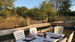 Una mesa de comedor al aire libre con sillas blancas, platos rosas y velas.