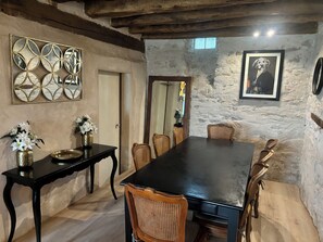 A rustic dining room with a long table, wicker chairs, and a decorative mirror.
