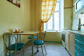 A kitchen with a dining table, chairs, and a window with curtains. - Home-Hotel Kostelnaya 3 (Kyiv)