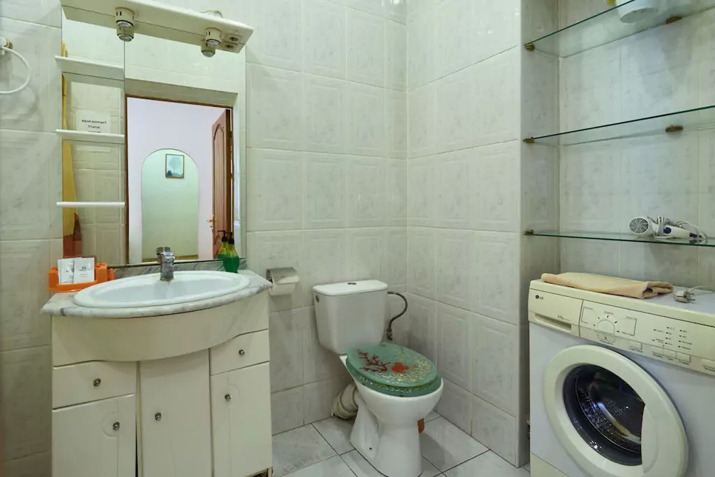 A bathroom with a sink, toilet, and washing machine.