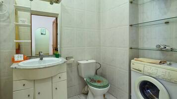 A bathroom with a sink, toilet, and washing machine.