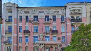 Un edificio rosa con detalles arquitectónicos ornamentales, varios balcones y una entrada central.