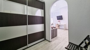 Una habitación moderna con puerta corredera, un escritorio con computadora, un televisor montado en la pared y una banca.