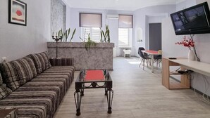 Una sala de estar moderna con sofá, mesa de centro, televisor y comedor con sillas y mesa.