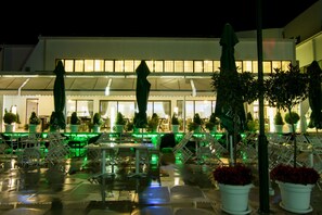 An outdoor seating area with tables and chairs, potted plants, and umbrellas. - Gardenia Hotel & Spa (Veles)