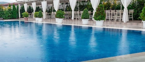 Una piscina techada, una piscina al aire libre de temporada, sombrillas