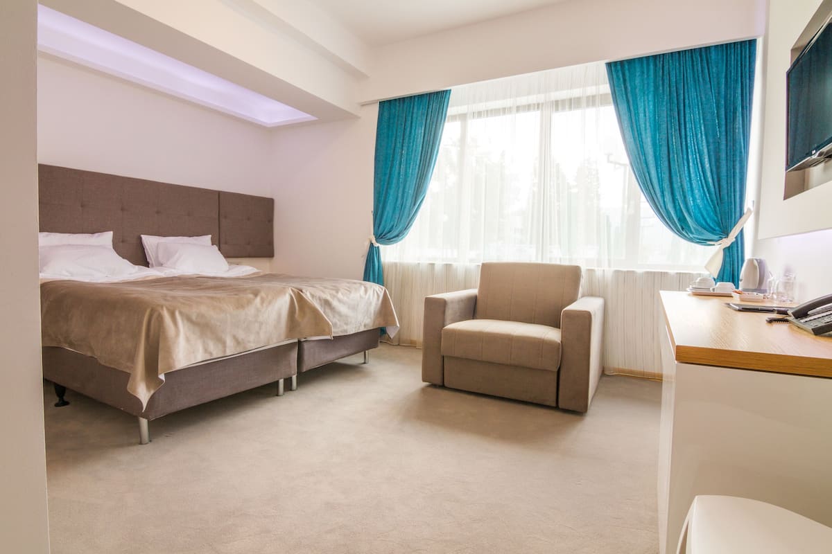 Una habitación de hotel con cama, una silla, un escritorio y televisión.