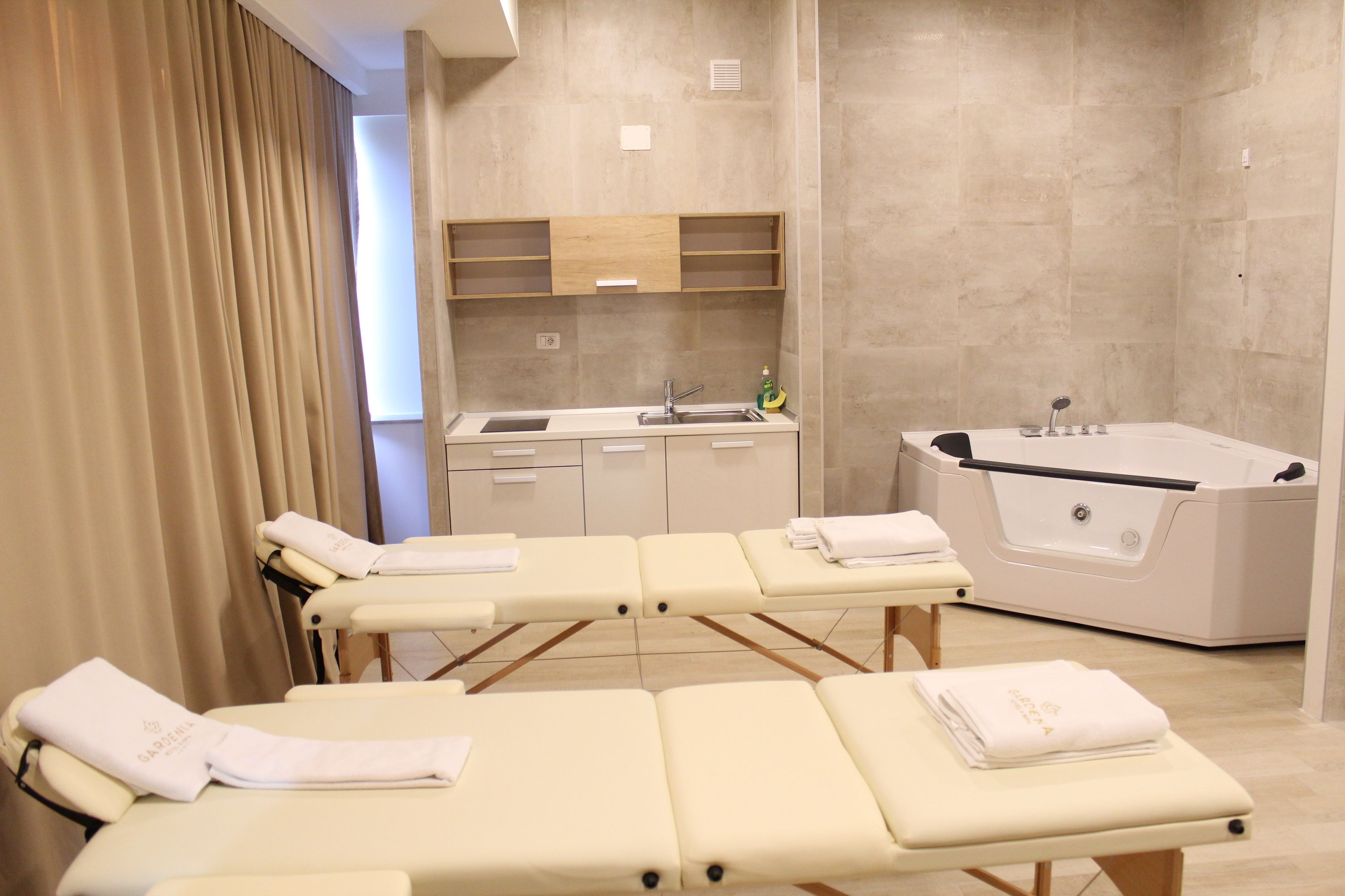 Un cuarto de spa con tres camillas de masaje, un lavamanos y una bañera.