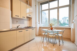 Una cocina con ventana, una mesa de comedor con sillas y un jarrón con flores.