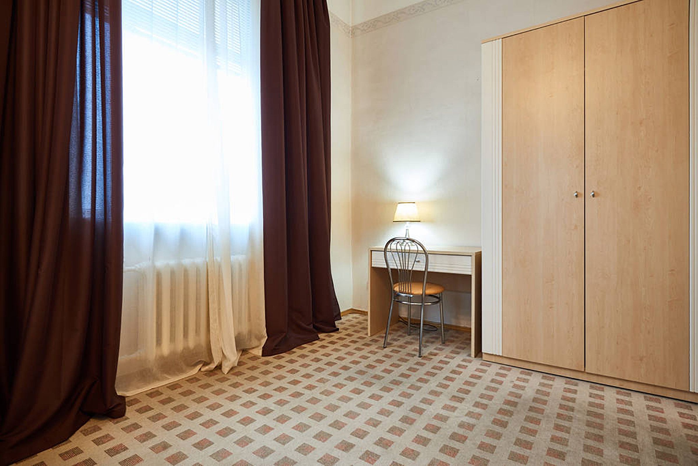 A room with a desk, chair, and wardrobe.