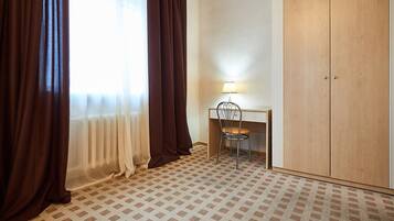 A room with a desk, chair, and wardrobe.