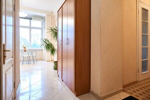 Un pasillo con un armario de madera, una planta en maceta y un comedor con sillas y una mesa.