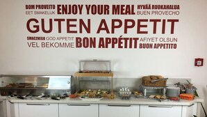 A buffet setup with various food items and a wall with multilingual 'Enjoy Your Meal' text. - Main Kinzig Hotel am Limes (Erlensee)