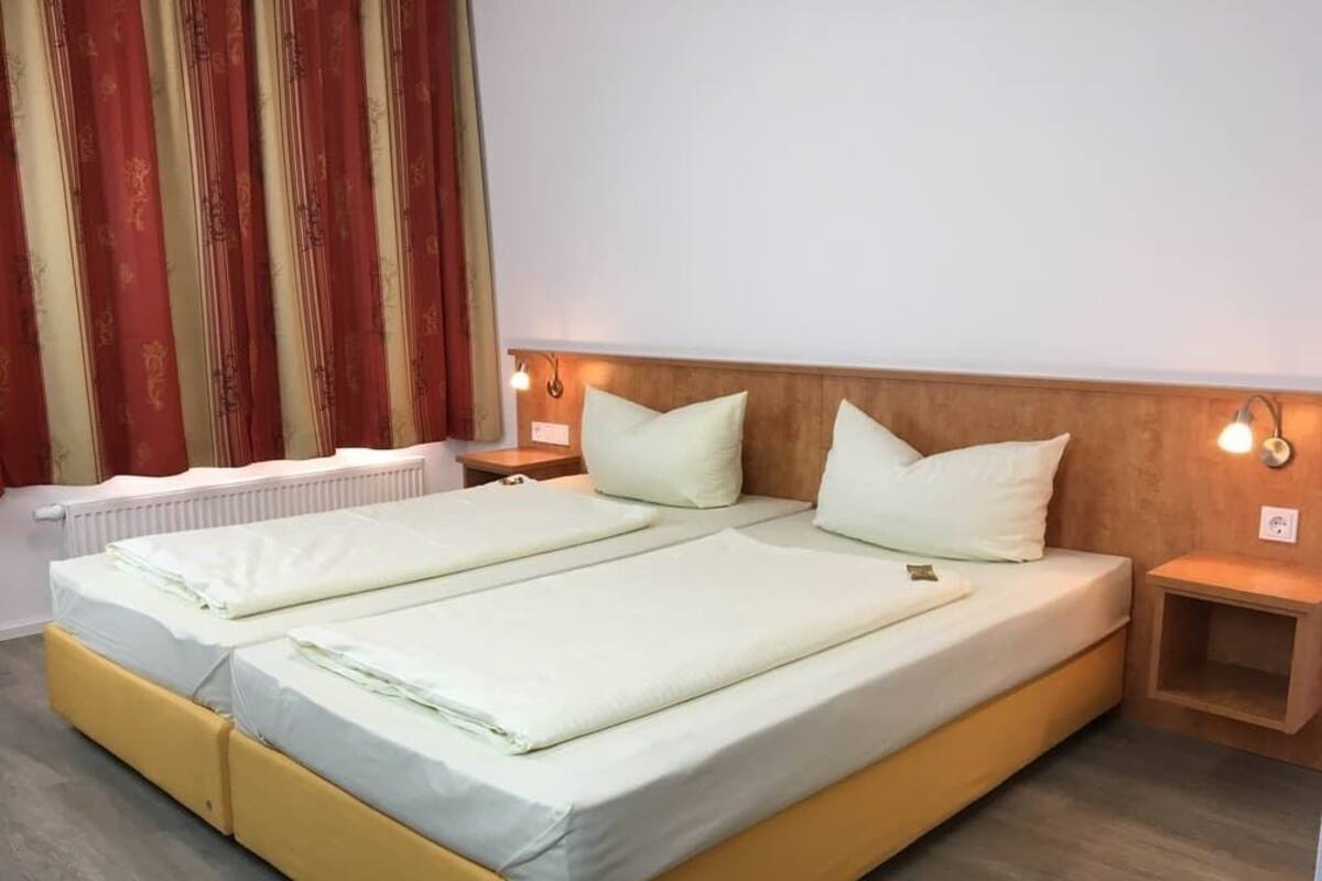 Ein Doppelbett mit zwei Kissen, ein Nachttisch, eine Wandlampe und eine Heizung.