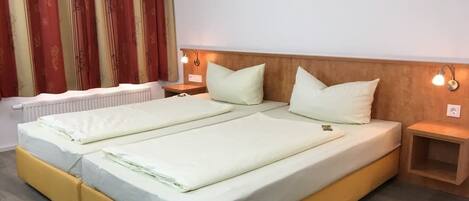 A double bed with two pillows, a wooden headboard, bedside tables with lamps, and a radiator.