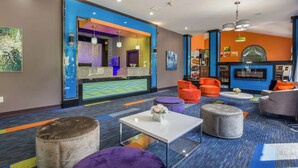 A modern hotel lobby with a reception desk, seating area, and a bar.