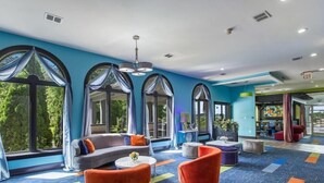 A modern hotel lobby with large windows, a sofa, chairs, and a coffee table.