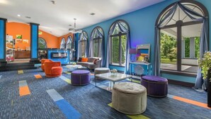 A modern hotel lobby with a colorful carpet, comfortable seating, large windows, and a view of the outdoors.