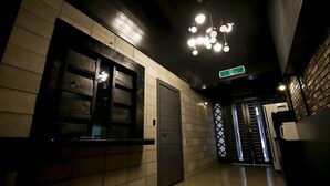Un couloir avec un comptoir d’accueil, une porte et un escalier menant à un autre niveau.