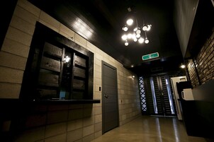 Un pasillo con un mostrador de recepción, una puerta y una escalera que sube a otro nivel.
