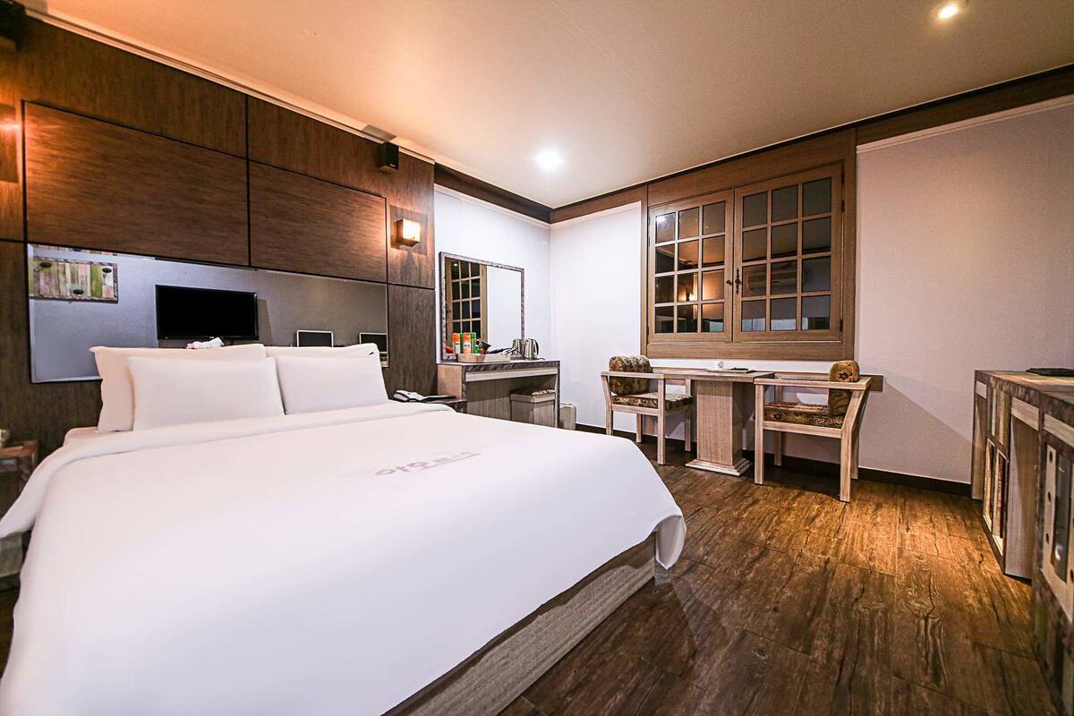 Habitación de hotel con una cama grande, un escritorio, una silla, un televisor y una ventana con vistas.