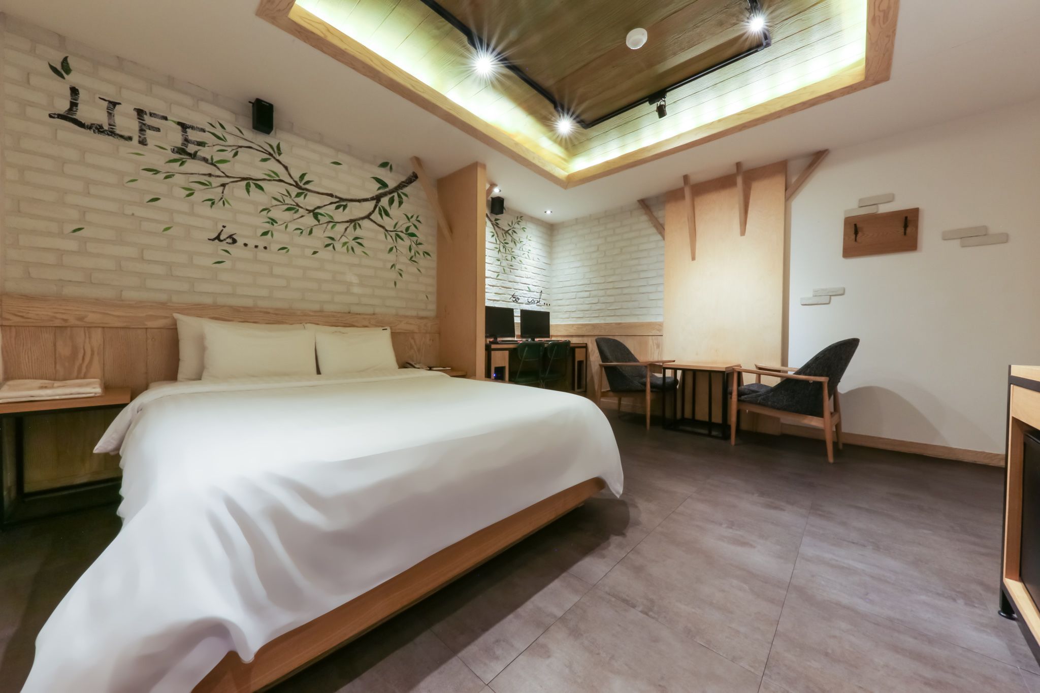 A modern hotel room with a large bed, a desk, and a chair.