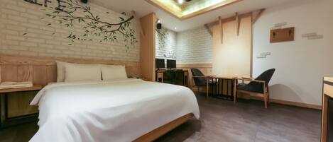 A modern hotel room with a large bed, a desk, and a chair.