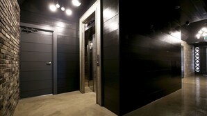 Un ascenseur moderne doté d’un écran numérique, un mur en briques et un sol poli dans un couloir.