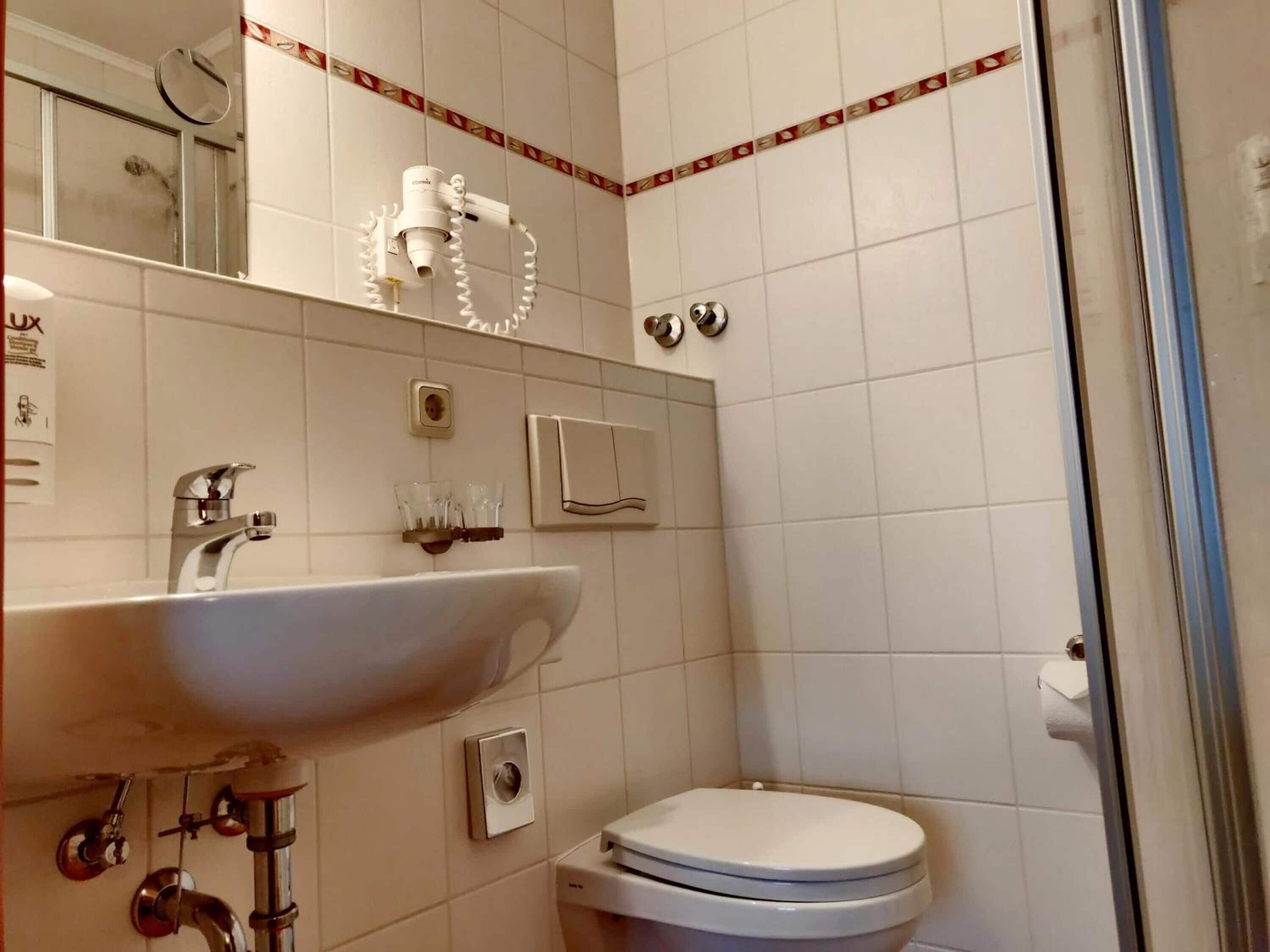 Ein Badezimmer mit Waschbecken, Spiegel, Toilette und Dusche.