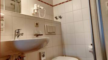 Ein Badezimmer mit Waschbecken, Spiegel, Toilette und Dusche.