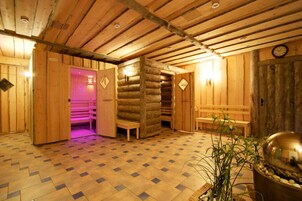 A wooden interior with a checkered floor, benches, and a sauna area with a pink light.
