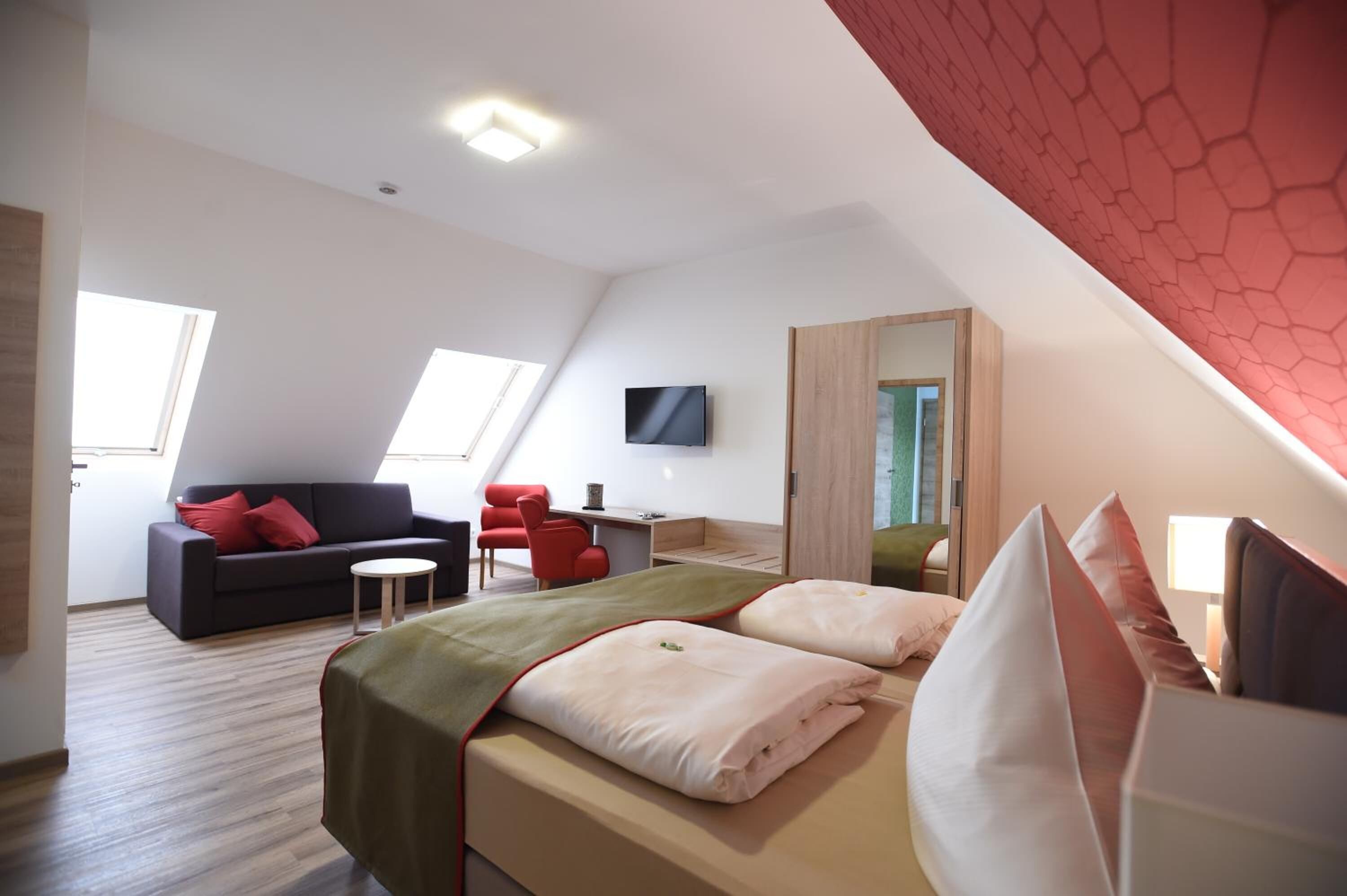 Una habitación de hotel moderna con cama, escritorio, sofá y televisor.