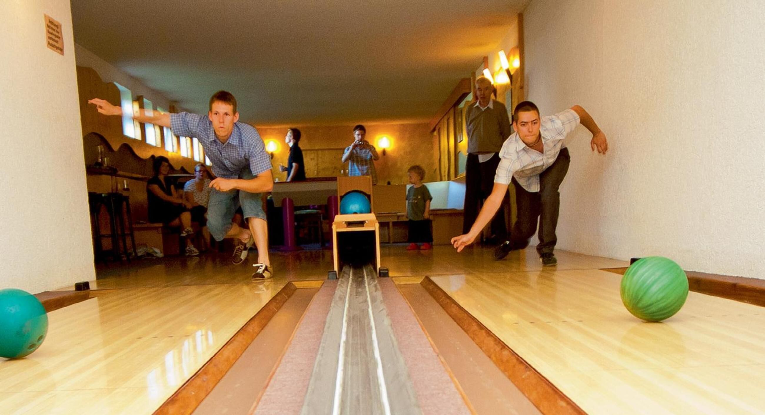 A bowling alley with lanes, bowling balls, and people playing.