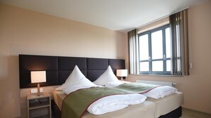 A hotel room with a large bed, two bedside tables, a window with curtains, and a headboard. - Hotel NEUE HÖHE (Klingenberg)
