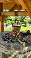 A rustic outdoor seating area with a stone fire pit, a bird sculpture, and a flower pot.