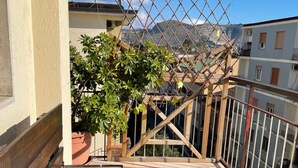 A balcony with a wooden bench and a small table, a potted plant, and a metal fence. - Sweet Emma (Caserta)