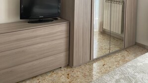 A bedroom with a wardrobe, a television on a dresser, and a radiator. - Sweet Emma (Caserta)
