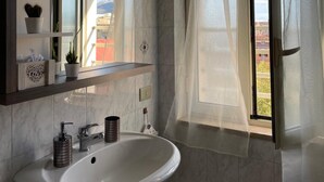 A bathroom with a sink, mirror, and window with curtains. - Sweet Emma (Caserta)